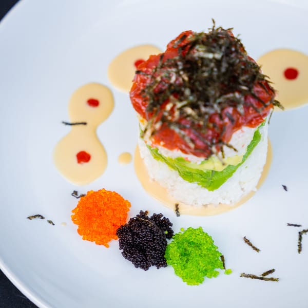 Sinju Sushi's colorful tuna tower with avocado, rice, and three types of tobiko on a white plate.
